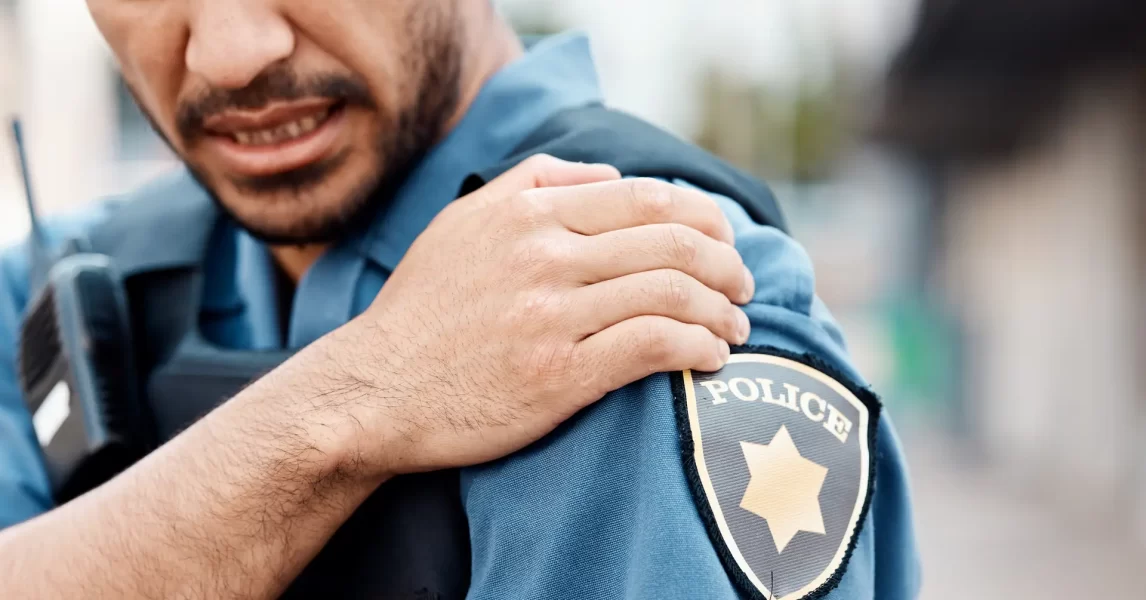 Police officer with injury, grabbing at shoulder while in uniform