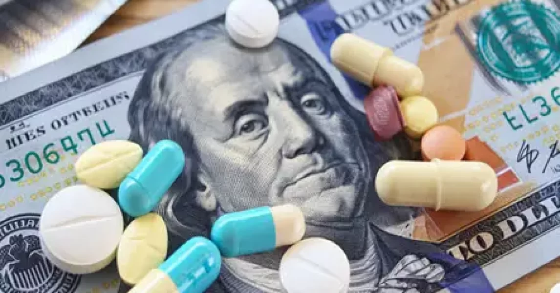 United States 100 dollar bill with medicine pills on top of it.