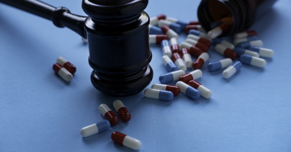 Medicine pills or capsules with a gavel on blue background
